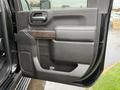 Close-up of the black interior door panel of a 2022 GMC Sierra 3500HD featuring a wood grain handle and textured gray fabric