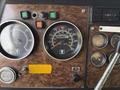 Close-up of the dashboard of a 1996 Kenworth T800 featuring several gauges including speedometer tachometer and fuel gauge with wood grain trim