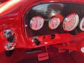 Dashboard of a 1962 Ford F-100 featuring round gauges for speed, fuel, and voltage surrounded by a carbon fiber panel and red accents