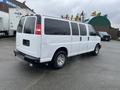 A white 2012 Chevrolet Express van with tinted windows and chrome wheels parked at an outdoor location