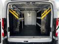 Interior view of a 2018 Ford Transit van showing shelving units with yellow safety stripes on either side and a partition at the back