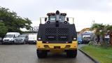 A 2019 Caterpillar 972M XE loader viewed from the rear with a large black grille and exhaust pipe prominently displayed