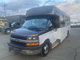 2017 Chevrolet Express with a black front and white body featuring large windows and a step for entry