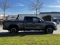 A 2023 Toyota Tundra in gray with black wheels parked on a grassy area showcasing its side profile and design features