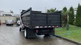 A 2021 International CV515 dump truck with a black cargo bed and white wheels, viewed from the rear