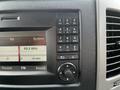 Dashboard control panel of a 2017 Mercedes-Benz Sprinter featuring a radio display and buttons for navigation and sound settings