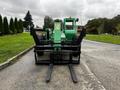 A green 2014 JLG 10054 telehandler with large black forks in the foreground facing forward