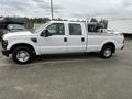 A white 2010 Ford F-250 Super Duty with a crew cab and a flatbed, parked sideways