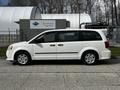 A white 2011 Dodge Grand Caravan parked, showcasing its side profile with four doors and alloy wheels