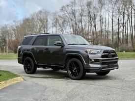 A 2021 Toyota 4Runner in a dark color with black alloy wheels parked on a gravel surface
