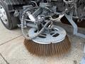 A 2009 UD Trucks UD 3300 with a large, round broom attachment featuring long bristle fibers for street cleaning purposes