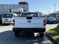 A white 2018 Ford F-150 truck seen from the rear with the Ford logo and model name visible on the tailgate