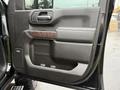 Close-up of the driver's side door panel of a 2022 GMC Sierra 3500HD featuring a wood-grain accent and controls for the windows and locks