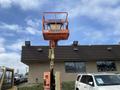 A 2009 JLG E300AJP articulated boom lift with an orange platform raised high above the ground, designed for reaching elevated work areas