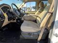 Interior view of a 2014 Ford F-350 SD with beige fabric seats and a black floor, showcasing the driver's seat and control panel