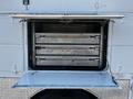 A 2004 Freightliner M2 service vehicle with an open storage compartment revealing three metal drawers labeled with various tools and equipment names