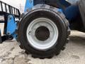 Close-up of a large black tire mounted on a blue forklift with a white rim and metallic lug nuts