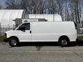 2015 Chevrolet Express white cargo van with no windows on the sides and chrome wheels parked on an asphalt surface