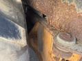 A close-up view of the rusted undercarriage of a 2008 Case Super 580M construction vehicle showcasing corroded metal and a large tire