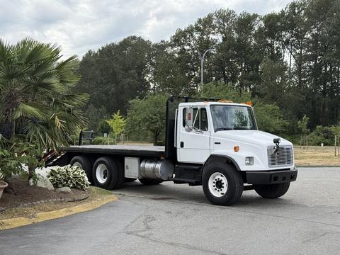 A white 1998 Freightliner FL80 flatbed truck with black accents and a visible chassis parked on a paved area