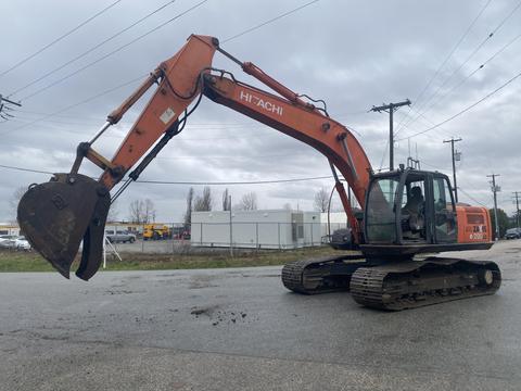 A 2006 Hitachi ZX200LC excavator with a long arm and a bucket attachment raised above its tracks