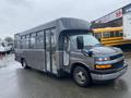 A 2017 Chevrolet Express bus with a dark exterior and a large front windshield displaying a yellow stripe on the hood