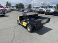 A 1999 Ez-go Industrial utility vehicle with a yellow and black color scheme featuring a cargo bed and a driver's seat.