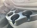 A black cup holder console with four indentations for cups in a 2008 Ford Econoline near the driver's seat