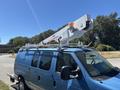 A blue 2008 Ford E-350 van with a mounted aerial lift on the roof