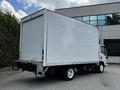 A 2018 Isuzu NPR box truck with a white, featureless cargo area and a flatbed chassis, showing the rear and side view of the vehicle