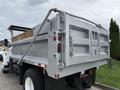 A 2004 Ford F-750 dump truck with a gray bed and a hydraulic lift system at the rear
