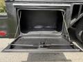 A rear storage compartment door of a black 2008 Ford F-550, opened to reveal an empty interior with a textured floor