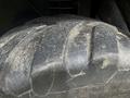 Close-up of a large, worn tractor tire with deep treads and dirt on its surface