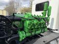 A bright green engine with various pipes and valves visible, mounted on a truck chassis with a focus on its industrial design and intricate details