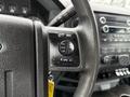 A close-up of the steering wheel controls of a 2015 Ford F-350 SD featuring buttons for media and volume adjustments