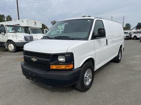 A white 2013 Chevrolet Express van with a black front grille and chrome wheels parked on a gray surface