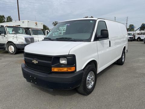 A white 2013 Chevrolet Express van with a black front grille and chrome wheels parked on a gray surface