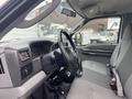 Interior view of a 2003 Ford F-450 SD showcasing the driver's side with a steering wheel and gray seat upholstery