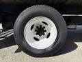Wheel of a 2023 Ford E-450 featuring a black lug nut cover and a white rim with a black tire mounted on it