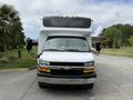 A white 2020 Chevrolet Express with a large front, black grille, and dual side mirrors parked on a paved surface