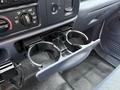 A dashboard of a 2001 Ford F-350 with a cup holder pulled out showing two cup slots and various control knobs and buttons