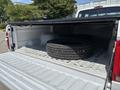 A 1995 Ford F-250 with a black tonneau cover opened revealing a set of stacked tires in its bed