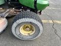 A close-up of a tire from a 2021 John Deere L Series S lawn mower showing a textured tread and a yellow hub