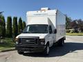 A 2013 Ford Econoline box truck in white with a front grill and large delivery box on the back, parked on a concrete surface.