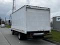 A 2013 Hino 195 box truck with a white exterior and a rear loading dock visible, parked on a street with industrial structures in the background