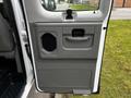 The interior door panel of a 2011 Ford Econoline featuring a handle a storage compartment and a speaker grille