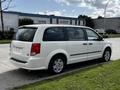 A 2011 Dodge Grand Caravan in white parked on the side of the road with a sliding side door and prominent rear hatchback design
