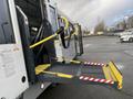 A 2018 Chevrolet Express with a foldable access ramp extended outwards featuring yellow and black safety bars and a textured surface for better grip