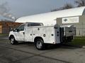 A white 2016 Ford F-350 SD utility truck with a service body and tool compartments on the side