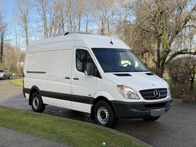 A white 2012 Mercedes-Benz Sprinter van with sliding side doors and a high roof with a sleek design and alloy wheels